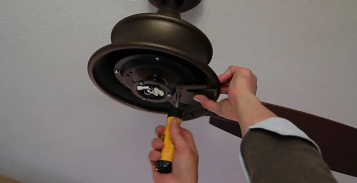 Electrician installing ceiling fan mounting bracket and fixture in Raleigh, NC