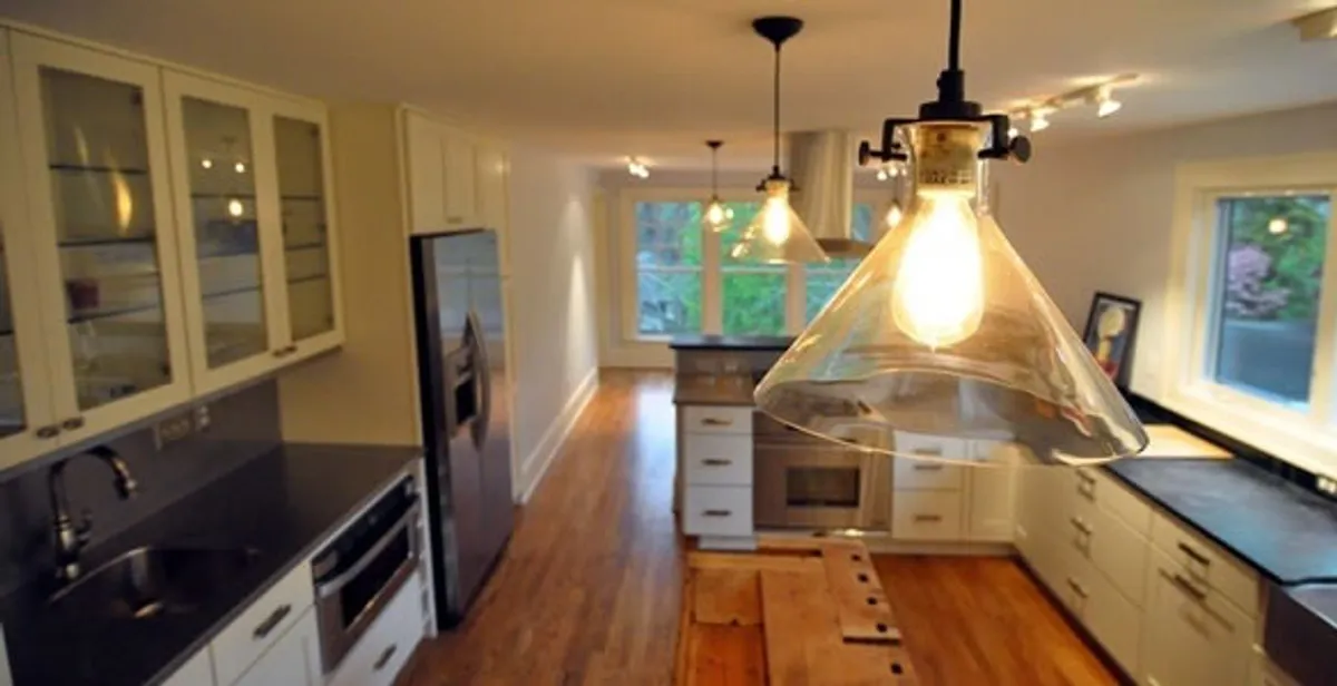 Residential electrician installing modern indoor light fixture in a home in Raleigh, NC